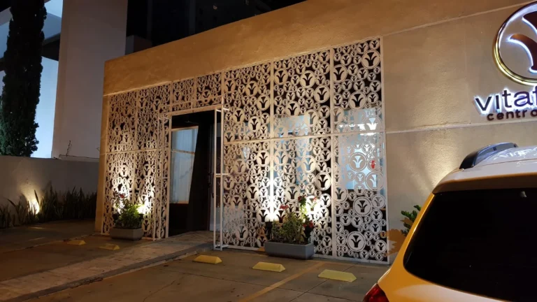 Fachada com painel vazado iluminado à noite